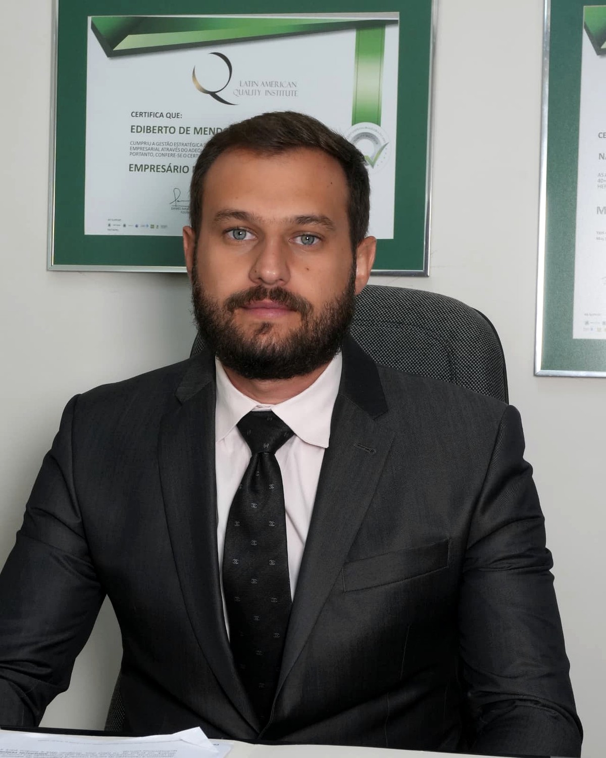 Dr. Ediberto de Mendonça Naufal em seu gabinete, com certificações ao fundo